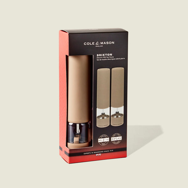 Cole & Mason Brixton Electric Mill Stone GS set in tan, displayed in its retail packaging, features two mills visible through a clear window. Each mill offers an adjustable grind and a durable ceramic grinding core for precise seasoning. The box is black and red with product details and images printed on the front.