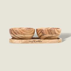 The Cole & Mason Portobello Olive Wood Pinch Pot Set features two small pots with unique grain patterns on a matching tray engraved with the brand name. The set is displayed against a plain, light beige background.