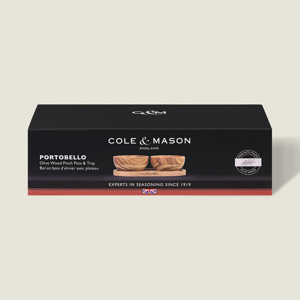 Black rectangular Cole & Mason box labeled Portobello Olive Wood Pinch Pot Set, showing unique grain olive wood pots with a seasoning tray, product image on front, and the text "Experts in Seasoning Since 1919.