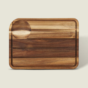 The Cole & Mason Berden Acacia Carving Board features a rectangular design with rounded corners, a recessed juice groove, and a circular indentation. Its striped acacia wood pattern adds style to your kitchen.