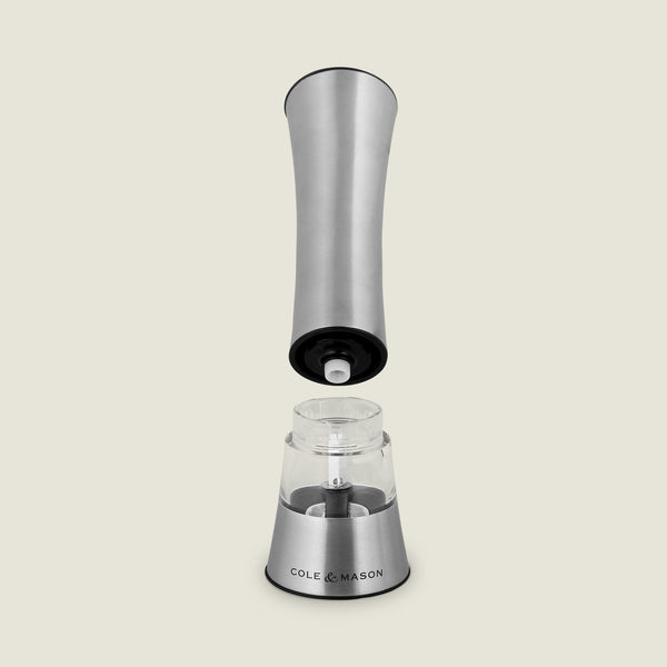 The Cole & Mason Burford Electronic Single Mill is a stainless steel pepper grinder with one-handed operation, adjustable grind settings, and a visible electronic mechanism when the top is lifted. The clear chamber is labeled “Cole & Mason.”.