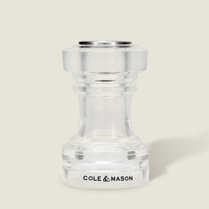 This simple, modern Acrylic Salt Shaker & Pepper Mill Set (104 mm) by Cole & Mason features a clear acrylic adjustable grinder, with the brand name displayed in black on the base against a light beige background.