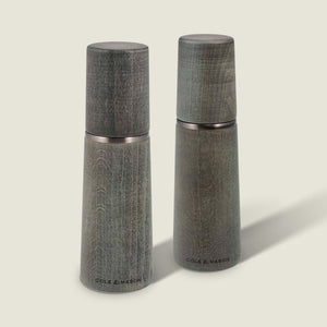 Two Marlow Grey Beech Salt & Pepper Mills by Cole & Mason UK, featuring a smooth tapered shape and wood grain, stand upright on a light background with an adjustable grinding mechanism for custom seasoning.