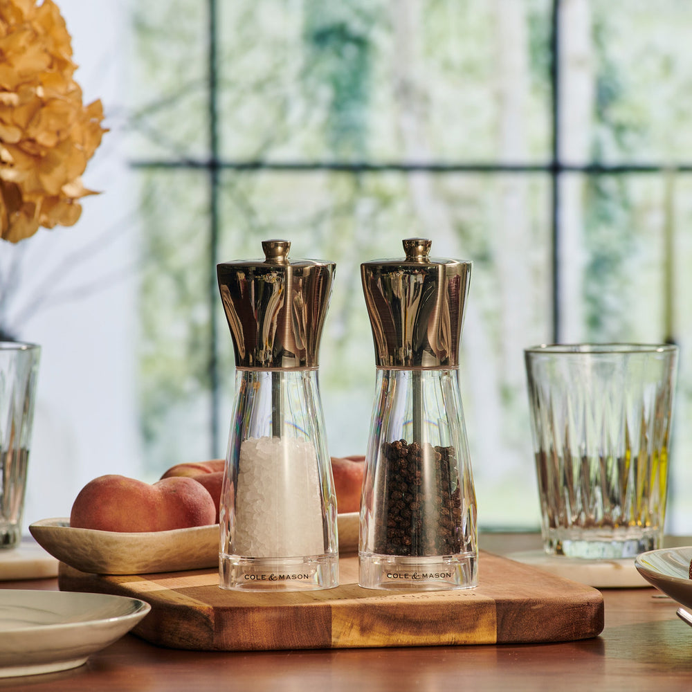 The Cole & Mason UK Rye Salt & Pepper Mill Set 160mm includes clear and stainless steel mills with ceramic mechanisms, pre-filled with coarse salt and whole black peppercorns.
