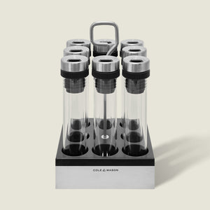 The Cole & Mason Shadwell Countertop Spice Storage features eight airtight glass jars in a stainless steel square holder with a metal handle for easy countertop organization.